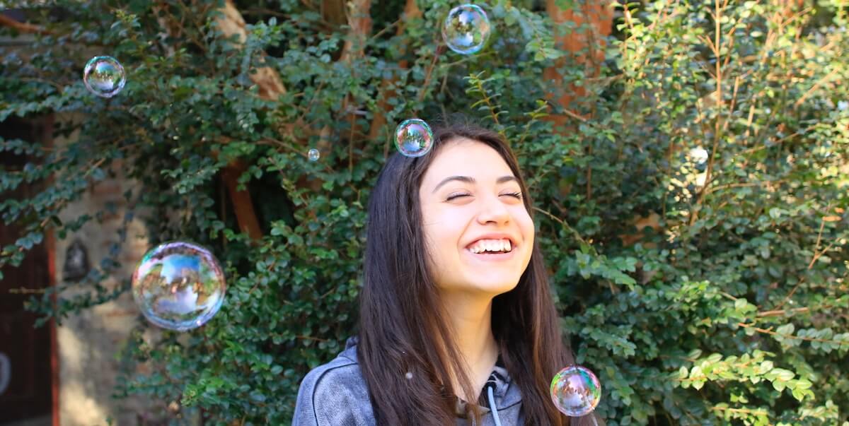 happy girl playing with bubbles in garden
